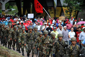 Honduran soldiers march next to supporters of the ousted president Manuel Zelaya during a protest near the Brazilian embassy