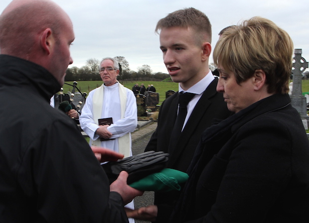 Mattie Casey of Comhairle Cuimhneacháin an Mhí removing the National Flag from Phonsie's coffin before presenting it with the IRA Volunteer's beret and gloves to Phonsie's son Kieran and wife Marie