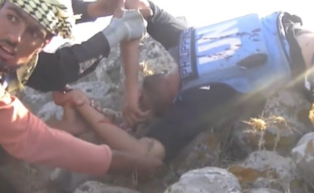 Rebel combat footage shows a wounded fighter, disguised as a UN peacekeeper, being dragged to safety after a failed ambush targeting Syrian Army positions in the Golan Heights