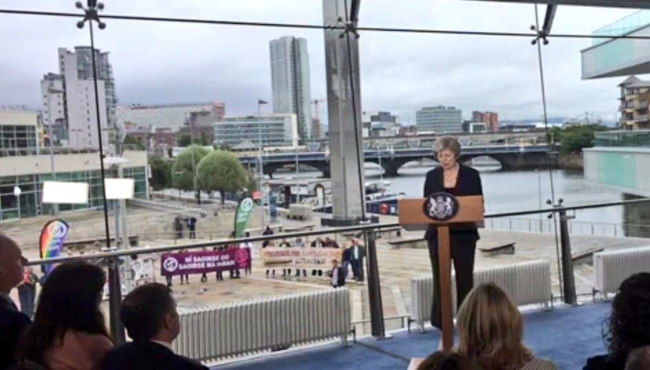 Protestors outside the Waterfront Hall during May's speech.