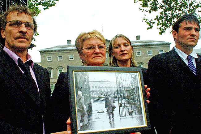 Fullerton Family - Albert (son), Dinah (wife), Amanda (daughter) and Eddie Jnr (son) outside Leinster House, carrying a 1984 photo of Eddie leaving Leinster House after a Labour Minister objected to his presence on a council delegation from Donegal