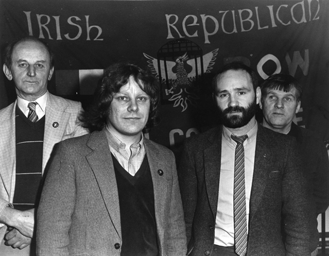 • 1985: Eddie Caughey in the background (right), with the late Oliver De Brún, another prisoners’ activist (background, left), former POW Gerry Mac Lochlainn and Alex Maskey at the relaunch of the POW repatriation campaign