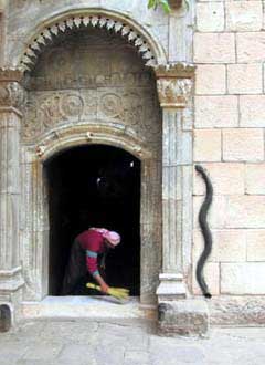 A Yezidi sweeps out the entrance to the tomb of Sheik Adi at Lalish - male Mrs Doyle doing the needful