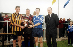 Gary Hurson, a nephew of Martin, being presented with the trophy by Brendan Hurson. Also in the picture are Brian McGurk of the beaten finalists Galbally and Dungannon Sinn Féin councillor Seán McGuigan