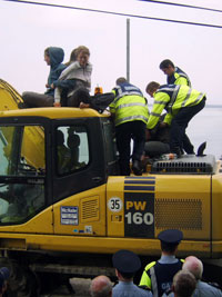 Protesters try to stop Gardaí using a JCB as a battering ram by climbing onto it