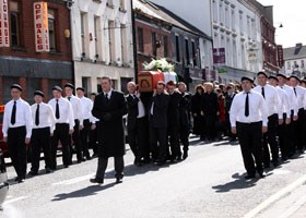 A republican honour guard escorts Seamus Trainor to his final resting place