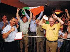 IN THE THICK OF IT: Tommy Devereux celebrates election victory for Cllr Noel Campbell (with Tricolour) and ex-POW Joe McHale with a clenched fist on one hand and a clipboard in the other