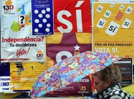 A woman walks past posters calling for the independence of Catalonia